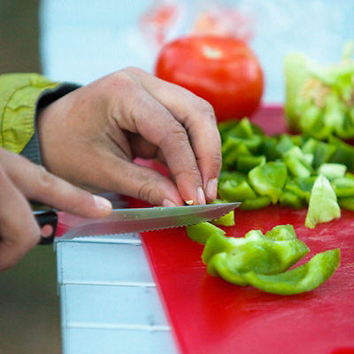 hand cutting peppers at a campsite
