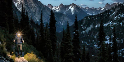 A hiker hikes along a trail by headlamp, in the North Cascades, Washington State.