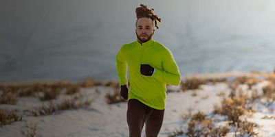 Male runner wearing long sleeves and gloves running in the snow