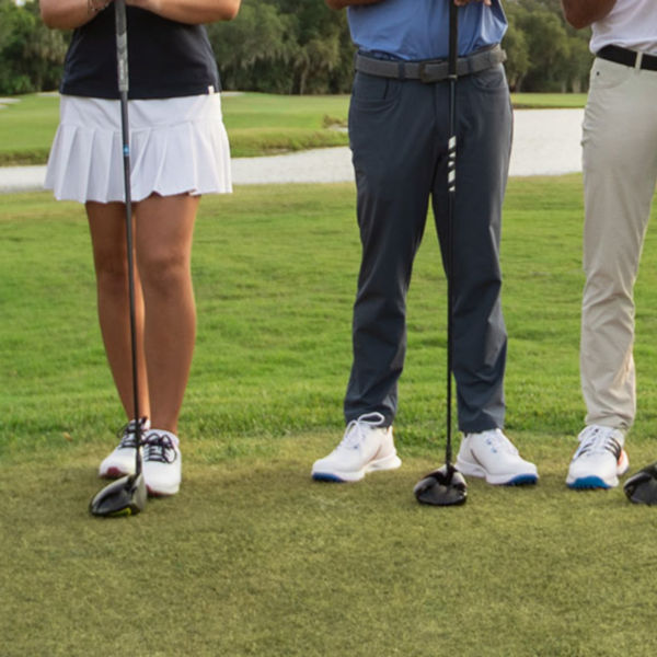golfers standing in a line, club in hand.