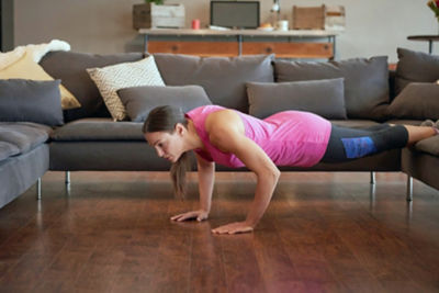Picture of a woman doing pushups at home with a couch as a place to rest her feet.