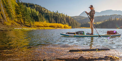 A woman standup paddleboarding in the fall