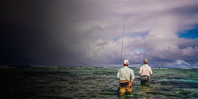 Anglers walk the outer reef of Alphones Island, Seychelles.