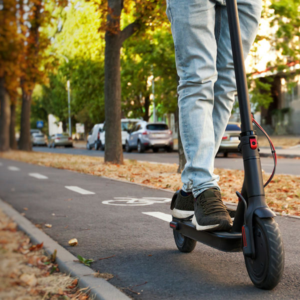 A person rides an electric scooter through the city by the pathways