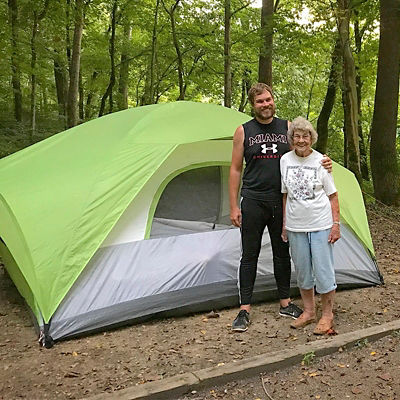 Grandma Joy and Brad Ryan pose in front of a tent