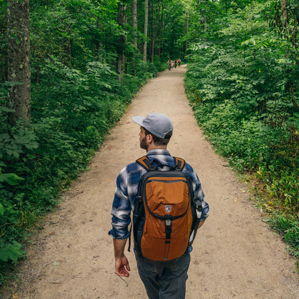 A man hikes on a lush green wooded trail