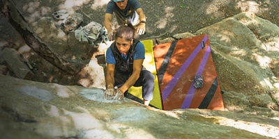 A man spots a woman as she boulders 