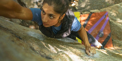 A woman grabs a hold while bouldering