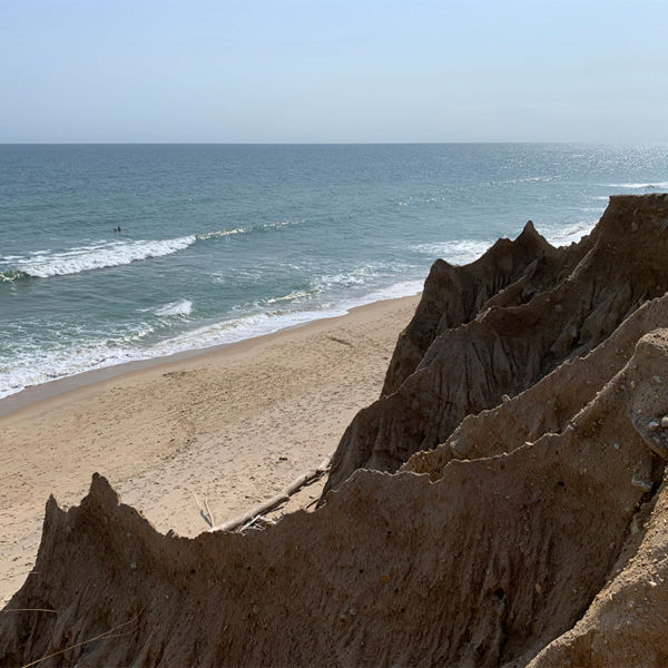 Cliffs edge overlooking the ocean and a lone surfer at Shadmoor State Park in Montauk, Long Island, New York