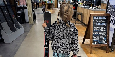 A girl walks with her skis after going to the Public Lands  store Ski and Snowboard tune up