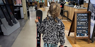 A girl walks with her skis after going to the Public Lands  store Ski and Snowboard tune up