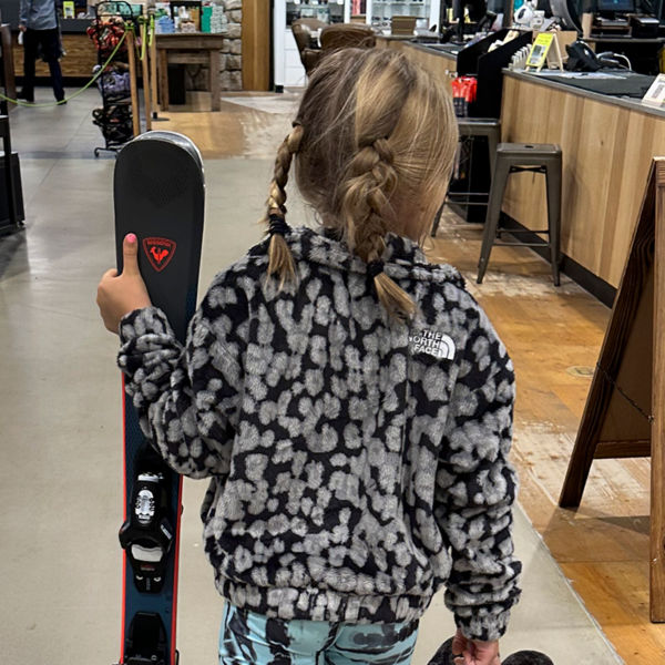 A girl walks with her skis after going to the Public Lands  store Ski and Snowboard tune up