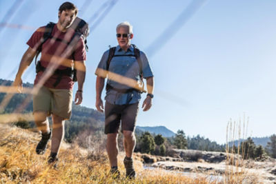 two men hiking on a mountain wearing shorts and backpacks