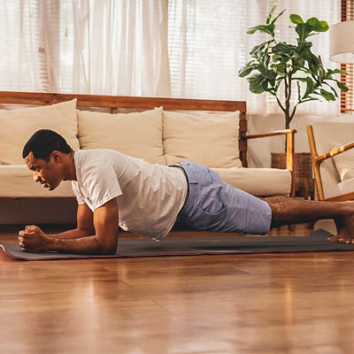 A man does a plank exercise in his living room