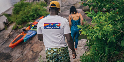 A man and woman walking down rocks next to a river.