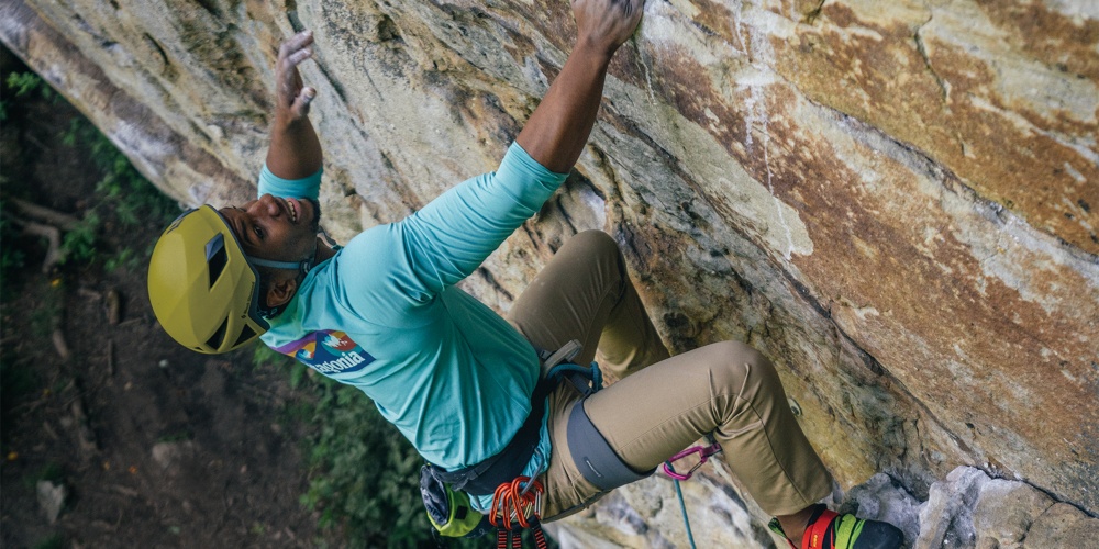 Premium Photo  A man climbing a boulder with a rock climbing outfit on his  hands.