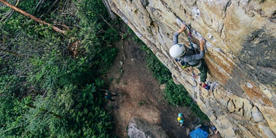 person in the wilderness climbing up a wall of rock