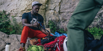 Male climber prepping his gear at the base of a rock wall