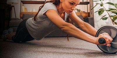 A woman works out at home with an ab wheel