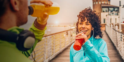 Man and woman drinking energy drink from bottle after a run