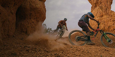 Two bikers cycling through rocky terrain