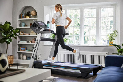 Image features woman running indoors on a treadmill