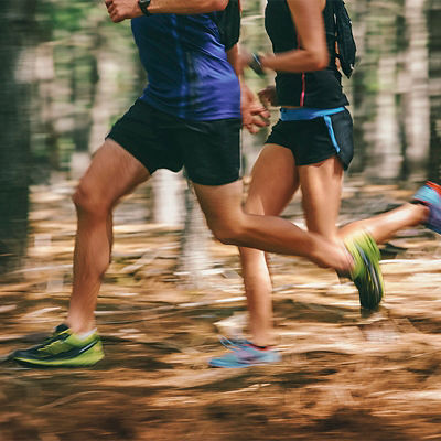 Couple running fast through the forest on trail run with motion blur