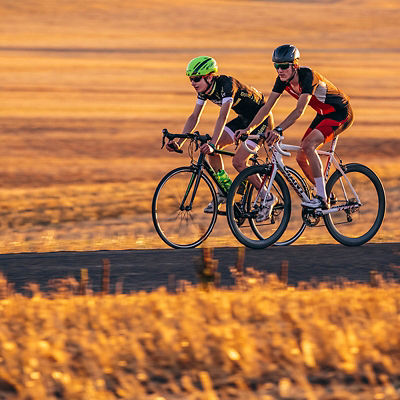 two cyclists training on bikes on a flat road