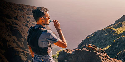 A man drinking energy sports nutrition energy gel while resting after trail running