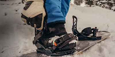 A person putting on snowboard boots