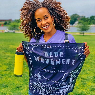 A woman holds a bandana for United By Blue