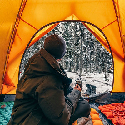 A person looks outside their tent in the winter