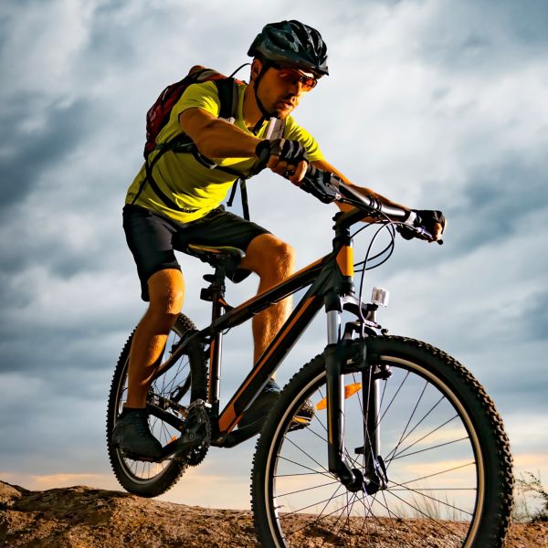 Cyclist Riding the Mountain Bike on Rocky Trail at Sunset.