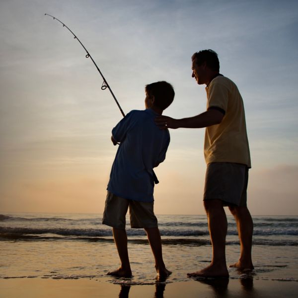 Man and young boy fishing in surf