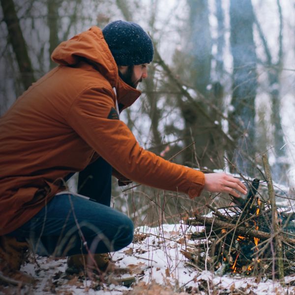 A man making camp fire in the winter woods