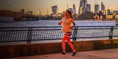 A pregnant woman runs on a path