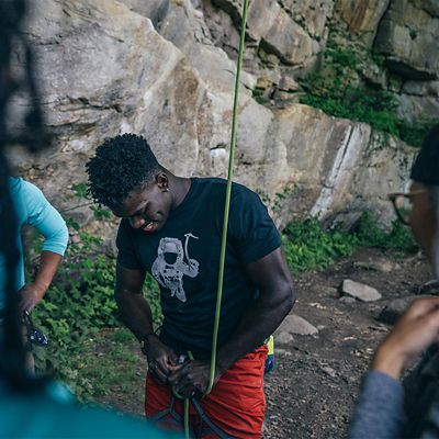 Climber getting prepped at the base of a rock wall