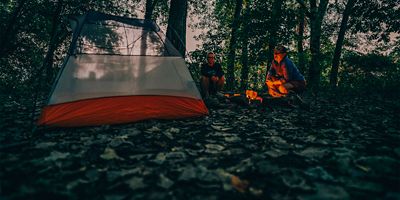 Two women sit by their tent on Sycamore Island