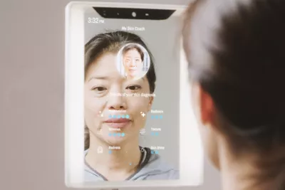 Older Asian woman looking at a CareOS Themis mirror to analyze her skincare. 