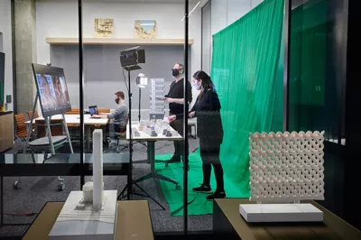 Employees of Perkins+Will in a New York office collaborating in a "Zoom Room" with remote workers in front of a green screen. 