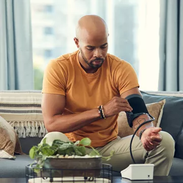 Black man checking his blood pressure with home diagnostics tools at home. 