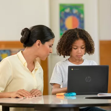 Teacher helping a child learn and bridge the digital divide on an HP laptop.