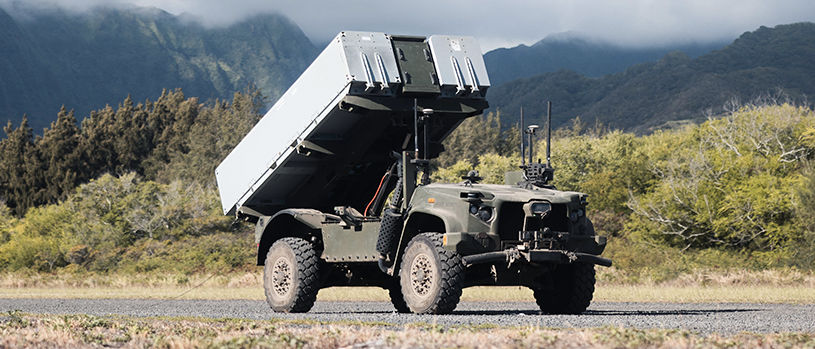 NMESIS anti-ship missile system mounted on JLTV with launcher raised in firing position against mountain backdrop.