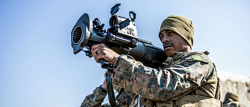 Marine with a FIM-92 Stinger missile launcher over his shoulder, aiming and about to fire. 