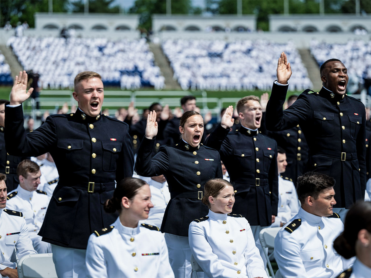 Marine officers in dress uniforms taking oath with raised hands during commissioning ceremony.