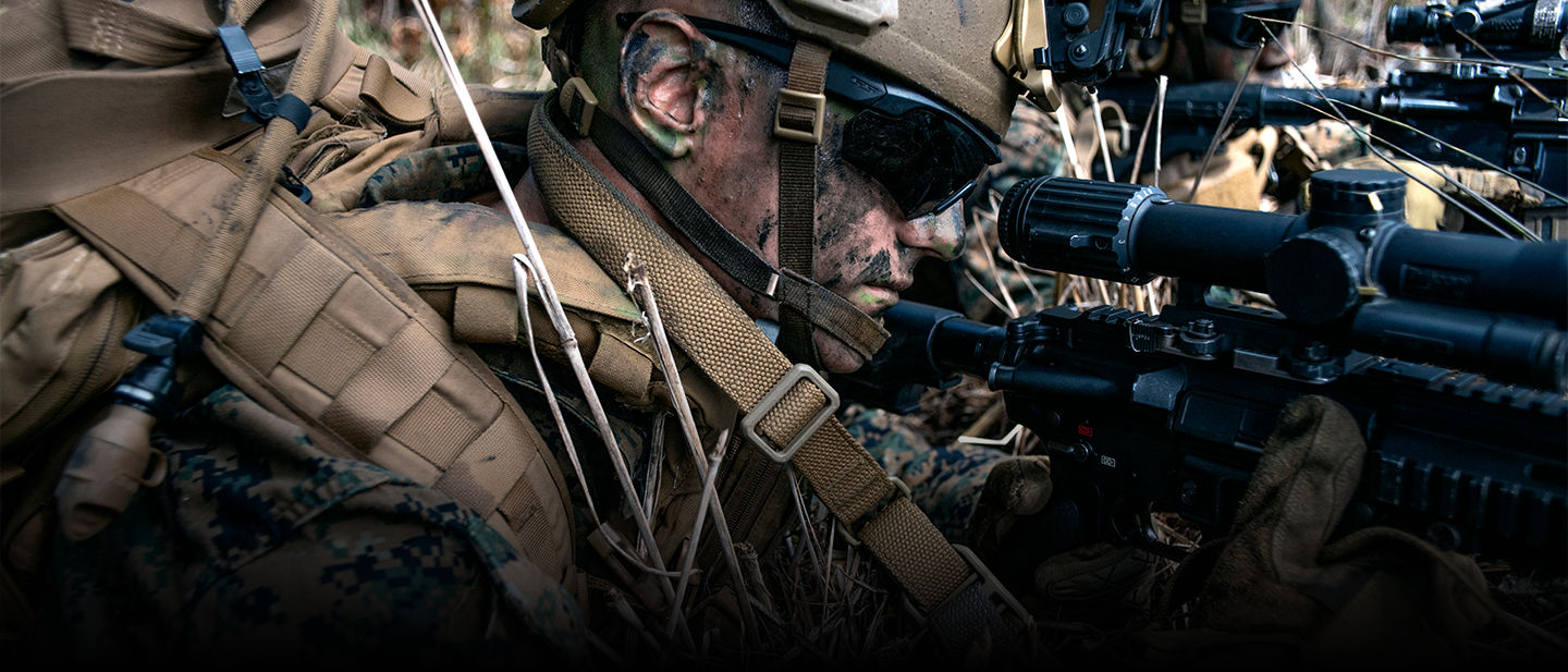 Marine with face camouflage looks down the scope of his rifle during a training exercise in Hawaii.