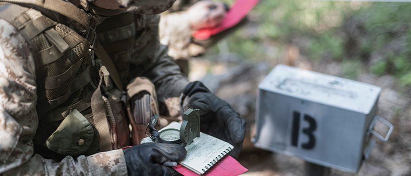 Officer candidate uses compass and map to navigate during Phase 3 land navigation training exercise.