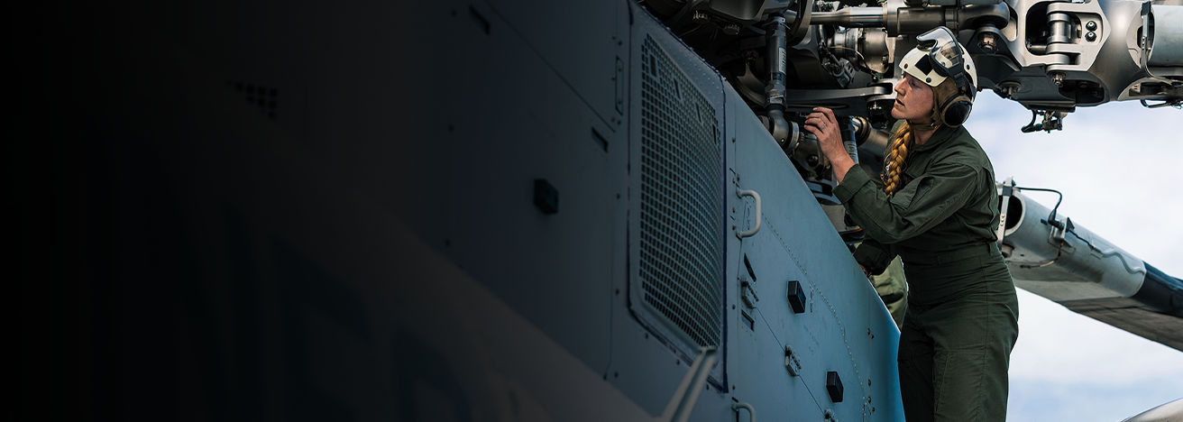 Captain Kricket Harper performs pre-flight inspection on helicopter engine compartment at Camp Lejeune.