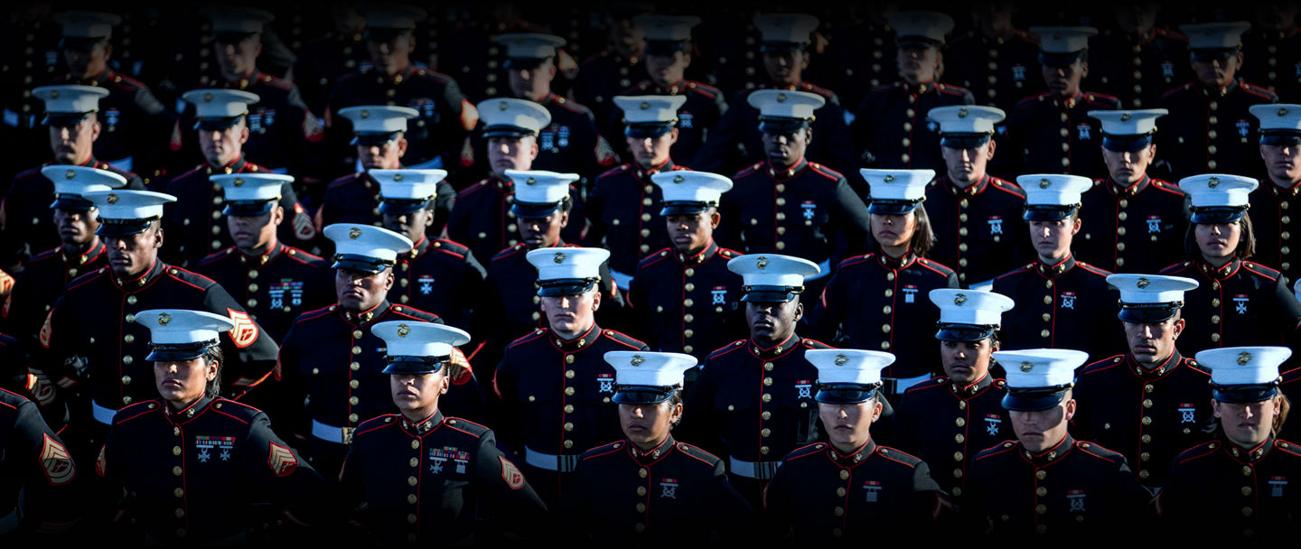 Marines in dress blue uniforms standing in formation at graduation ceremony after completing boot camp.
