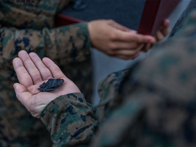 Marine recruit holds Eagle Globe and Anchor emblem in hand during EGA ceremony at Parris Island marking completion of training.
